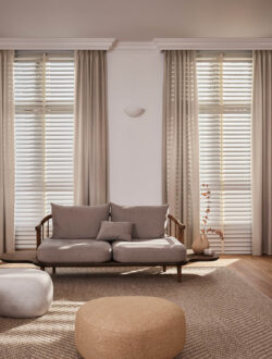 Lange Luxaflex® stofgardiner der hænger i en stue, hvor der står en sofa.